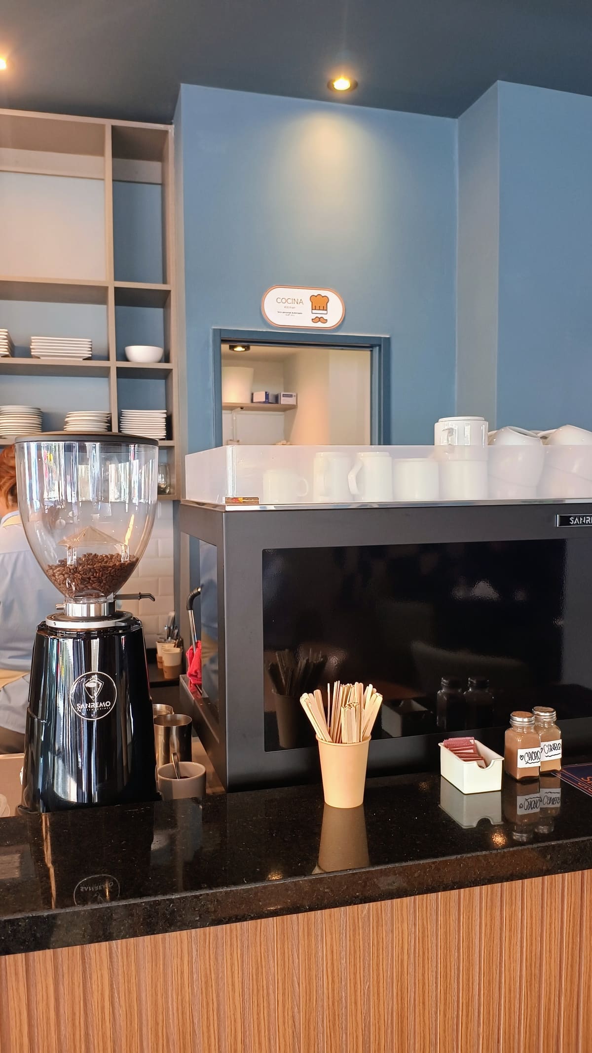 Barra de Francis Coffee & Bar: molinillo, máquina de café y la pared azul del salón