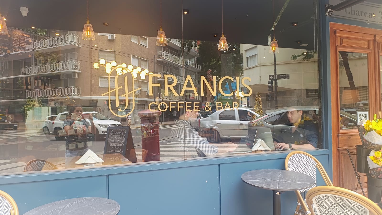 Vidriera de Francis Coffee & Bar con el imagotipo en vinilo dorado sobre el vidrio y el salón detrás